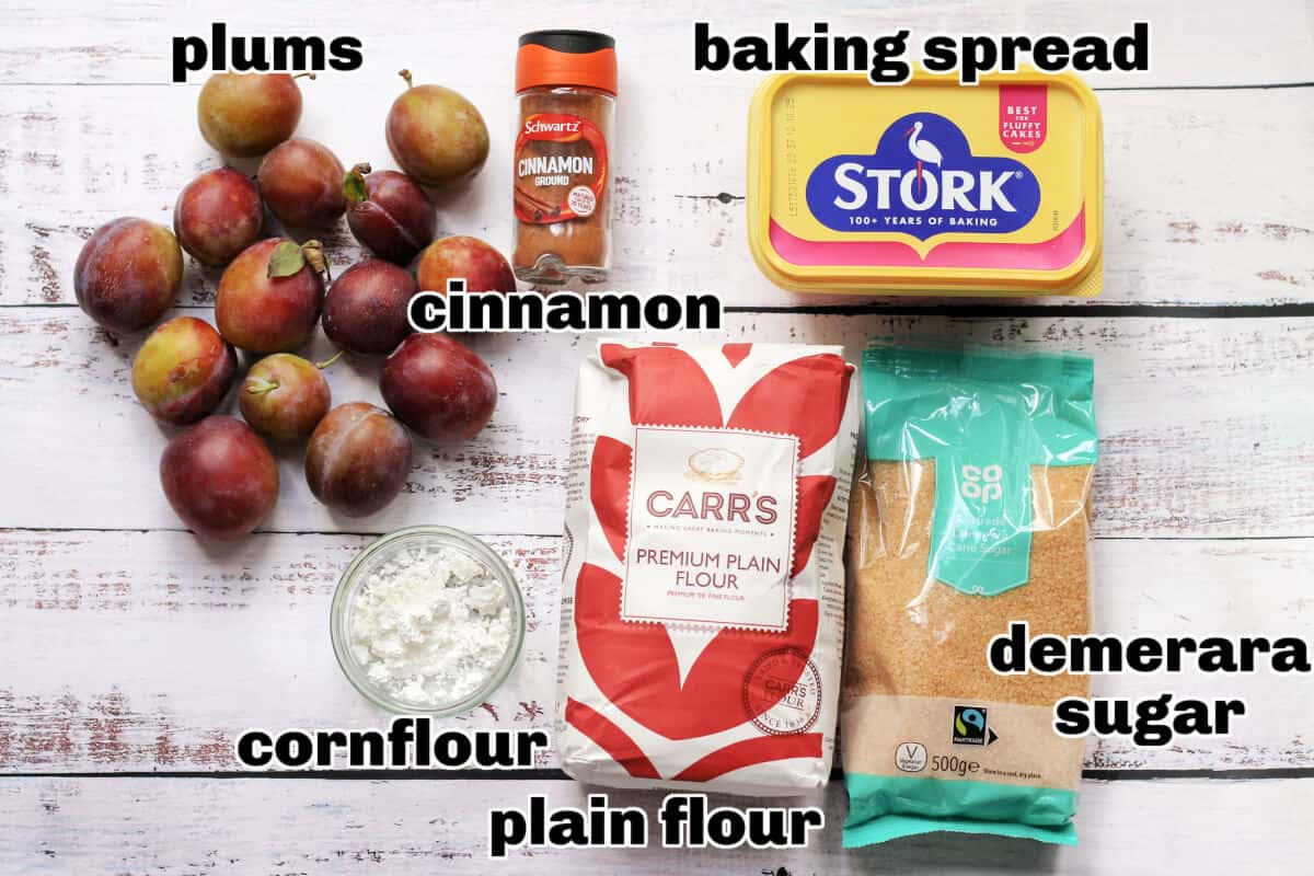 Labelled ingredients for plum crumble on white board.
