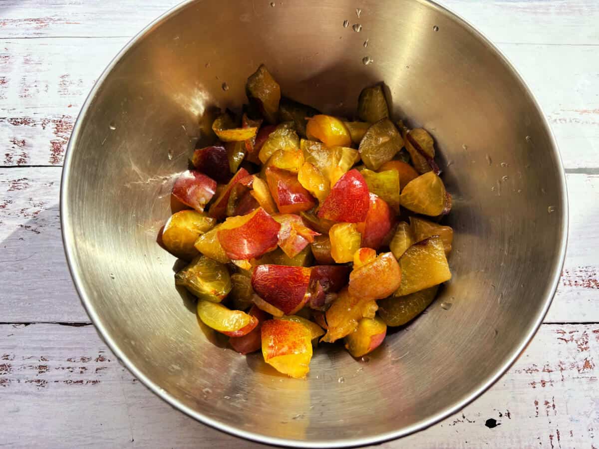 Chopped plums in a metal bowl.