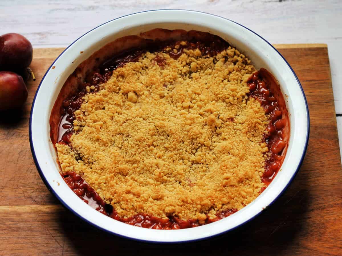 Baked plum crumble with juices oozing out of the sides.