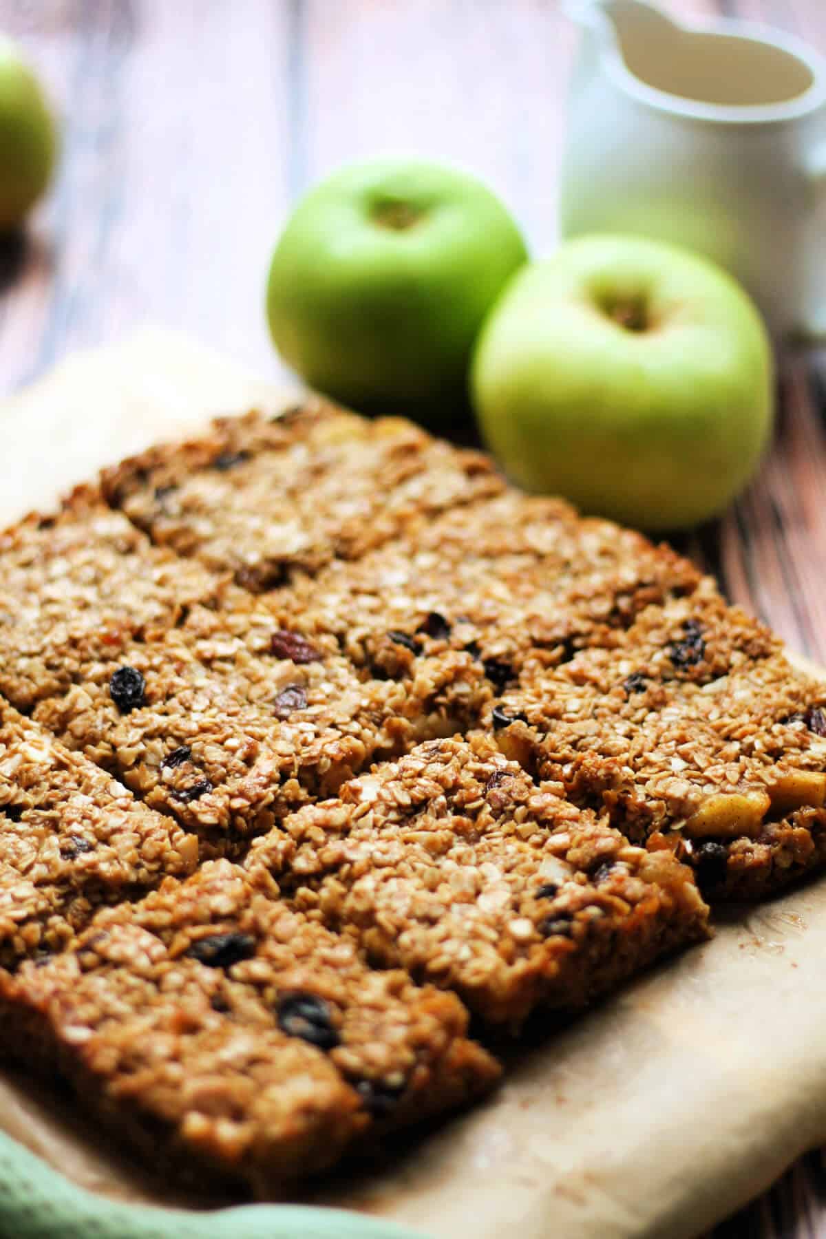 Flapjacks on baking paper with apples in background.