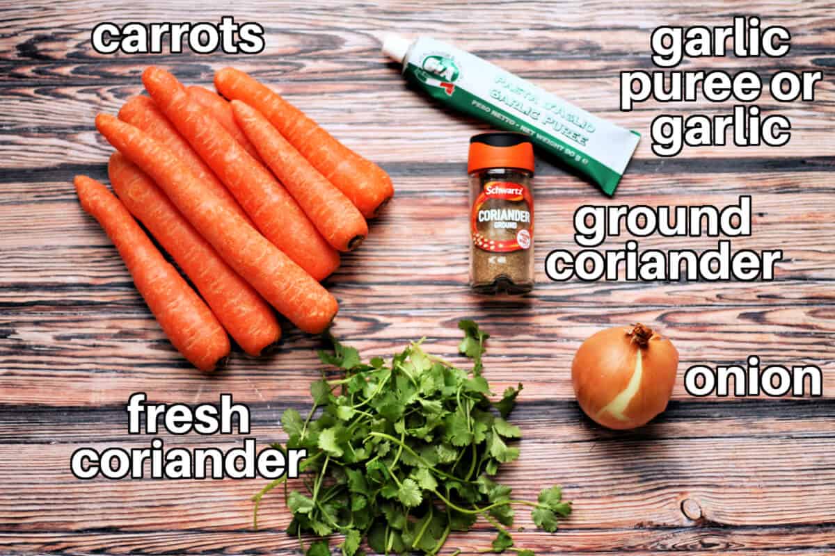 Labelled ingredoents for carrot soup on wooden table.
