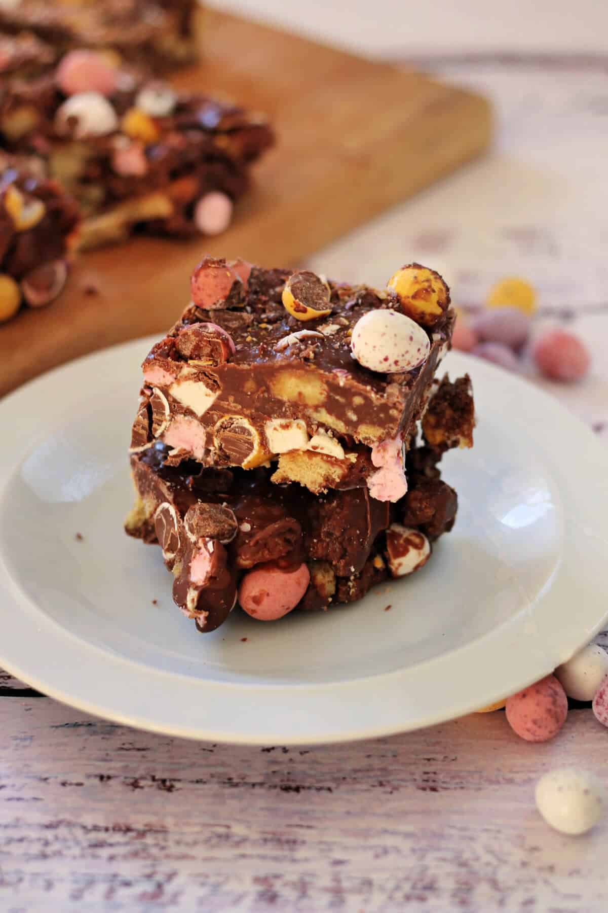 Two pieces of rocky road stacked on a white plate.