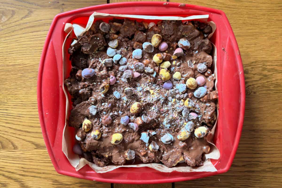Rocky road topped with crushed mini eggs, in pan.