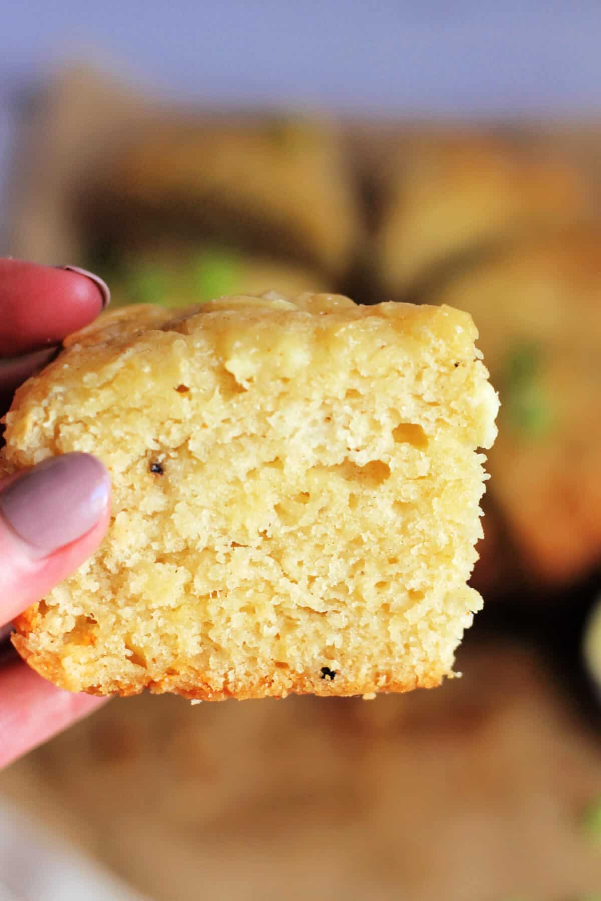 A cheese scone held up in a hand, showing the soft crumb within.