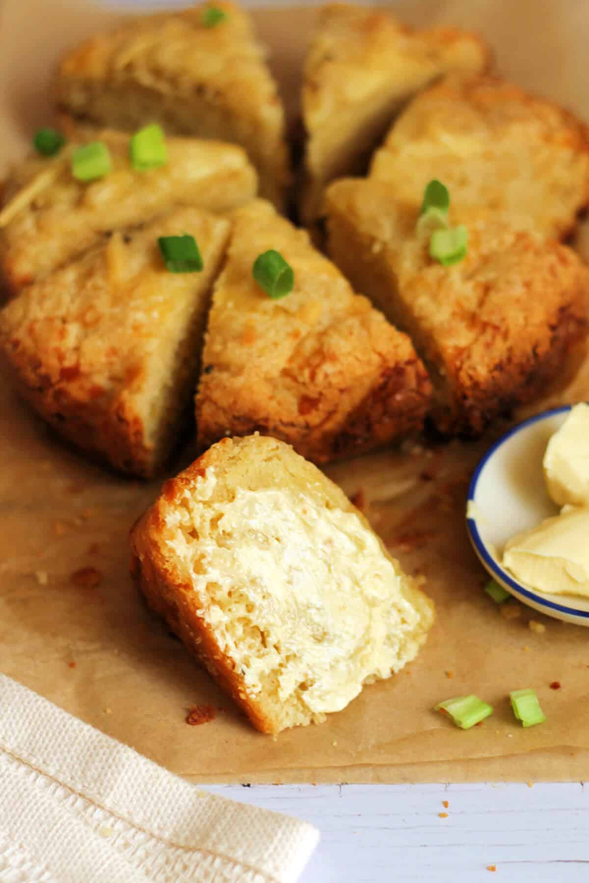 Triangle cheese scone spread with butter on a table.