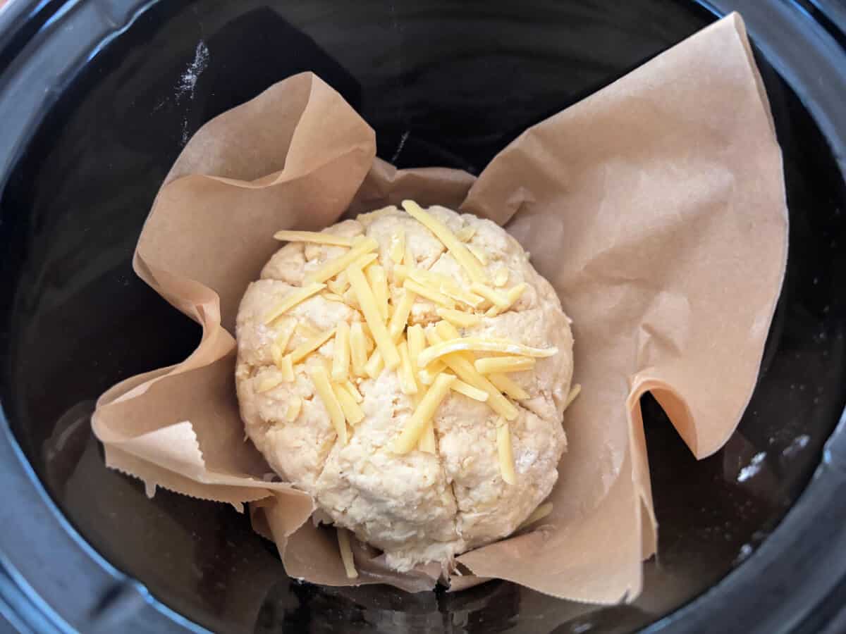 Scone round placed into slow cooker pot on a folded sheet of baking paper.