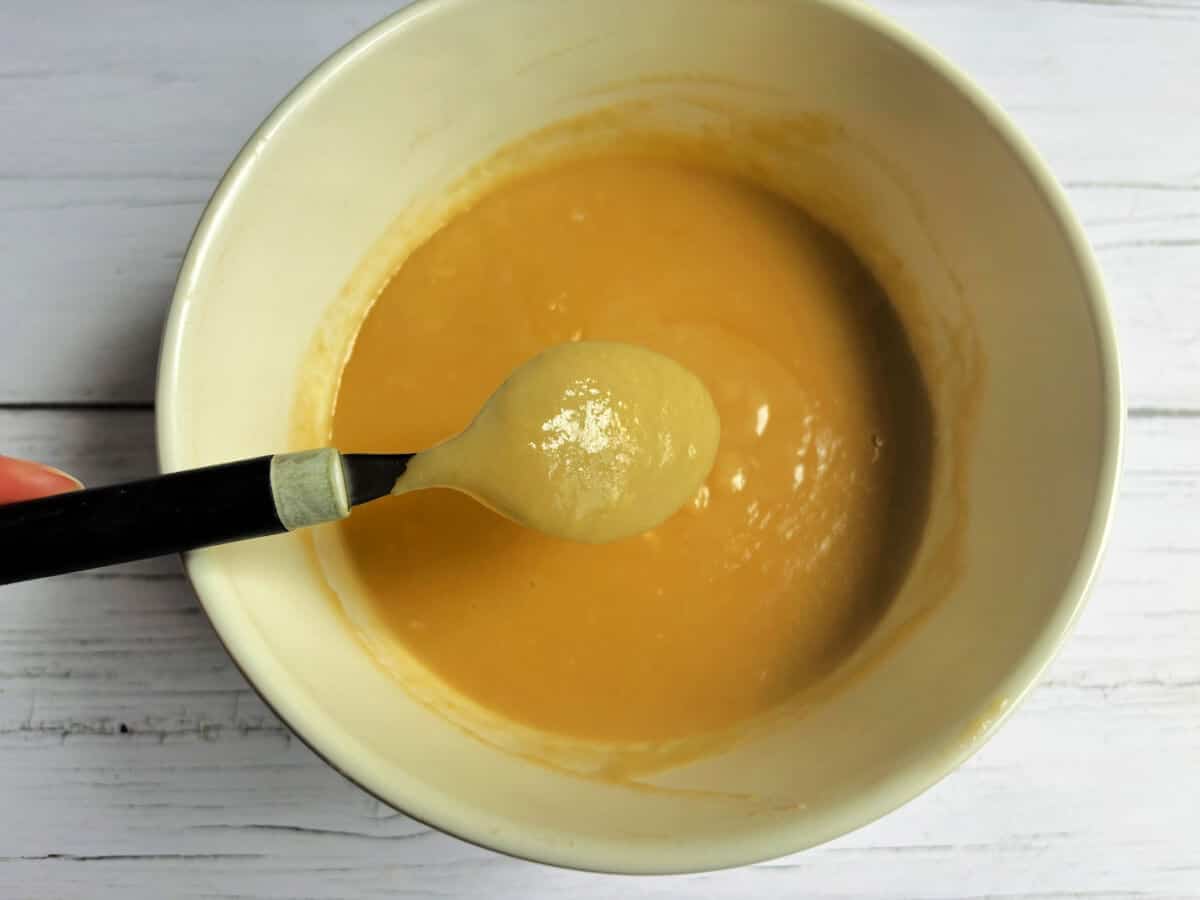 Curd in a bowl, teaspoon held above bowl showing it is coating the back of a spoon.